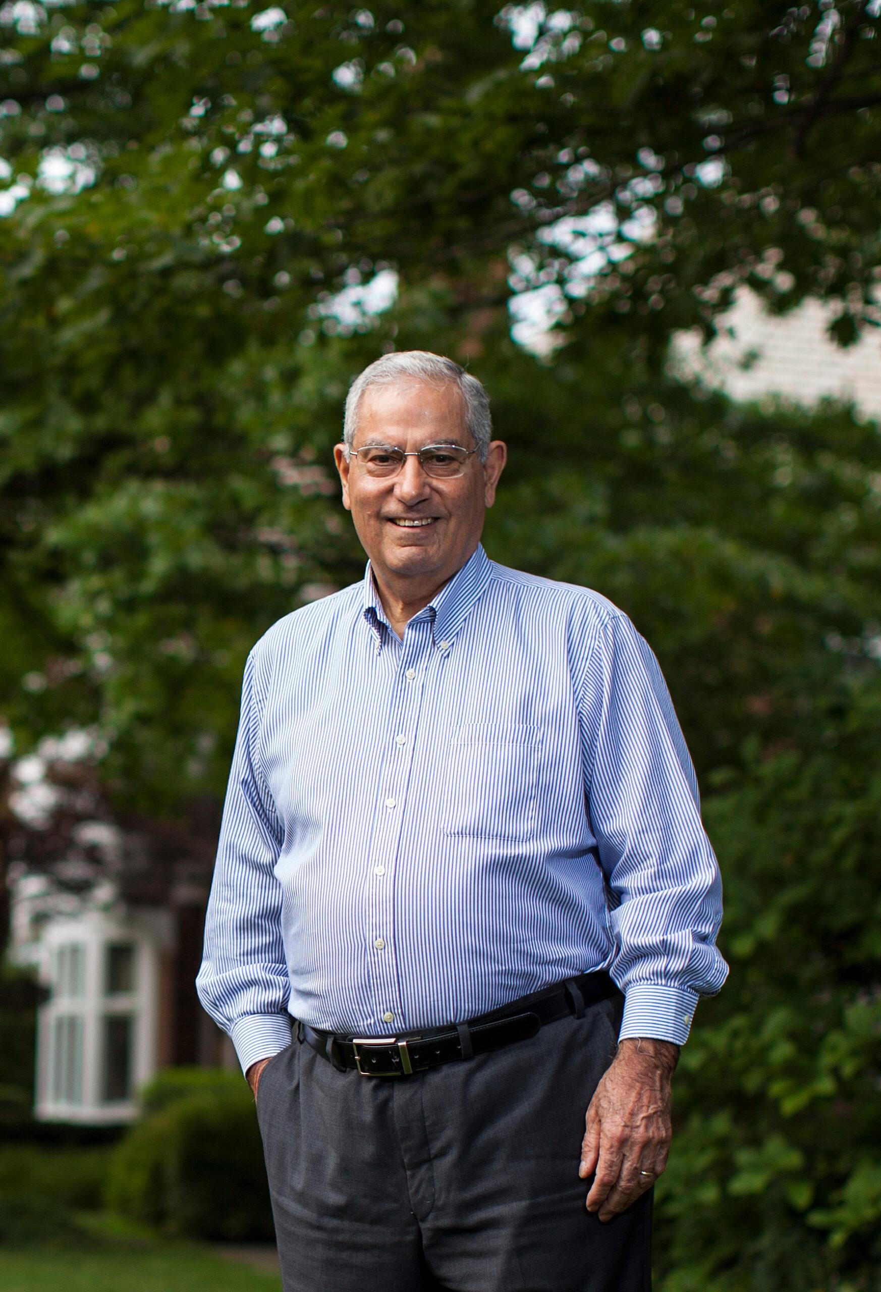 Dr. Faramarz Ismail-Beigi portrait with nature background and Dr. Faramarz is dressed up facing the camera and smiling with one hand on the pocket.