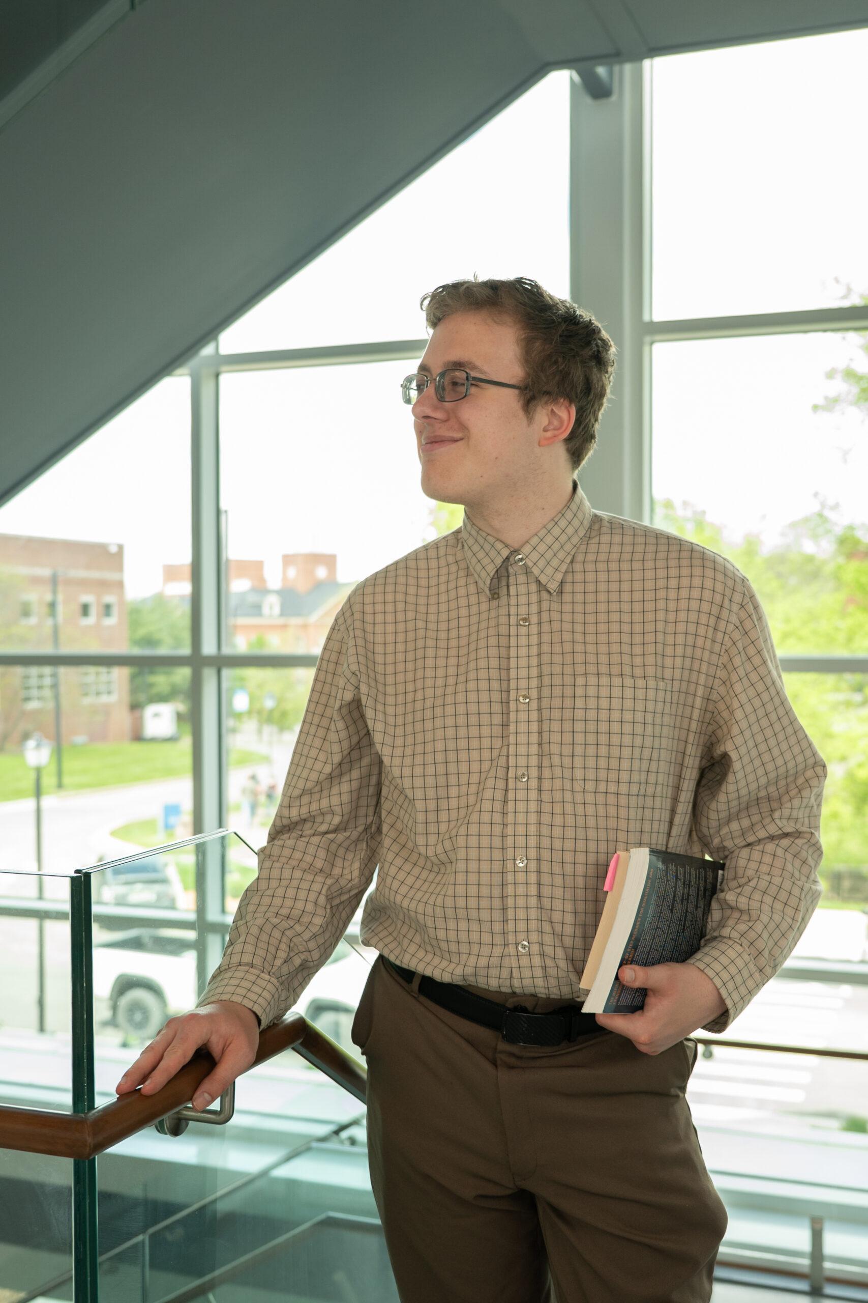 Student, Sam, standing and holding books